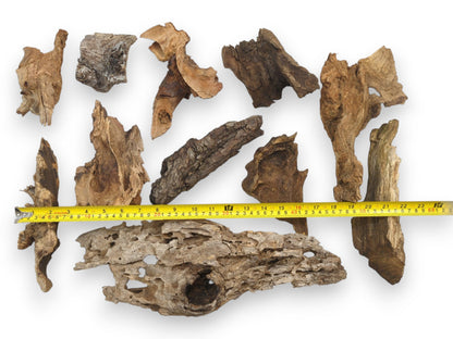 An assortment of natural raw wood chunks with a yellow tape measure indicating their various lengths.