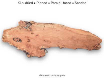 A long, irregular timber slab with a smooth, reddish face and a decaying live edge.