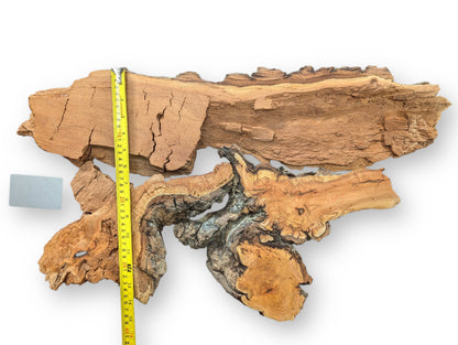 Two irregular, textured brown and grey willow wood pieces, yellow measuring tape, grey block.