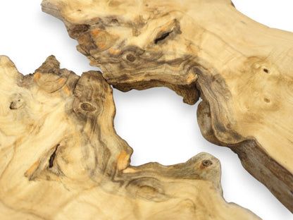 A close-up of two wood pieces reveals eye-like knots within dark, wavy grain patterns.