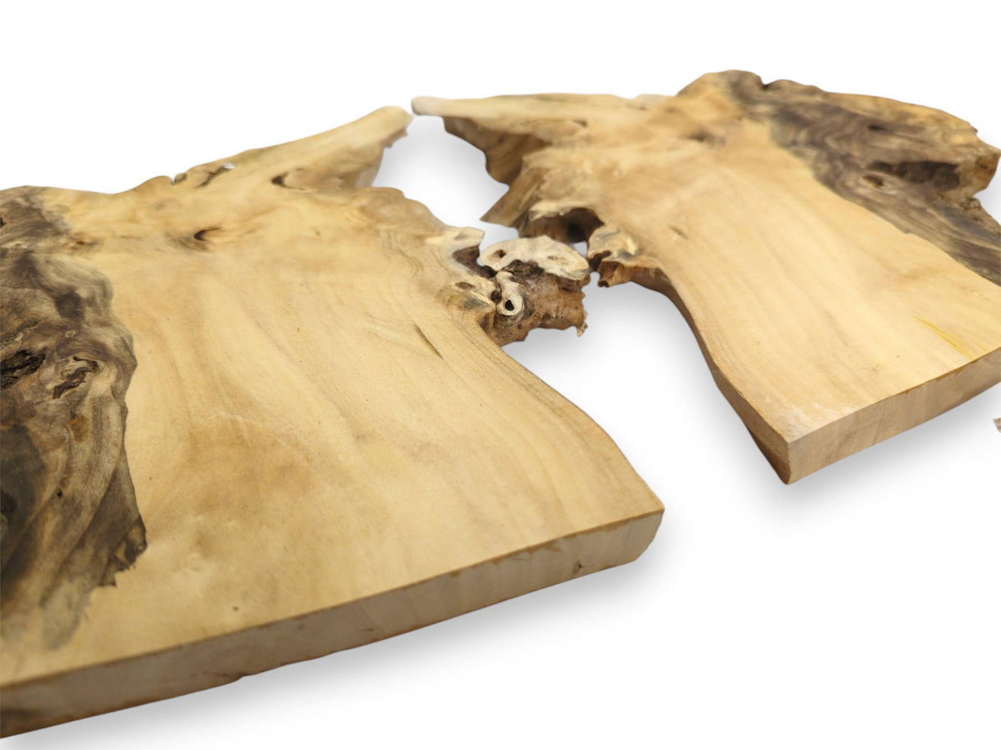 Two thick lumber sections show smooth pale faces and dark, craggy live edges nearly touching.