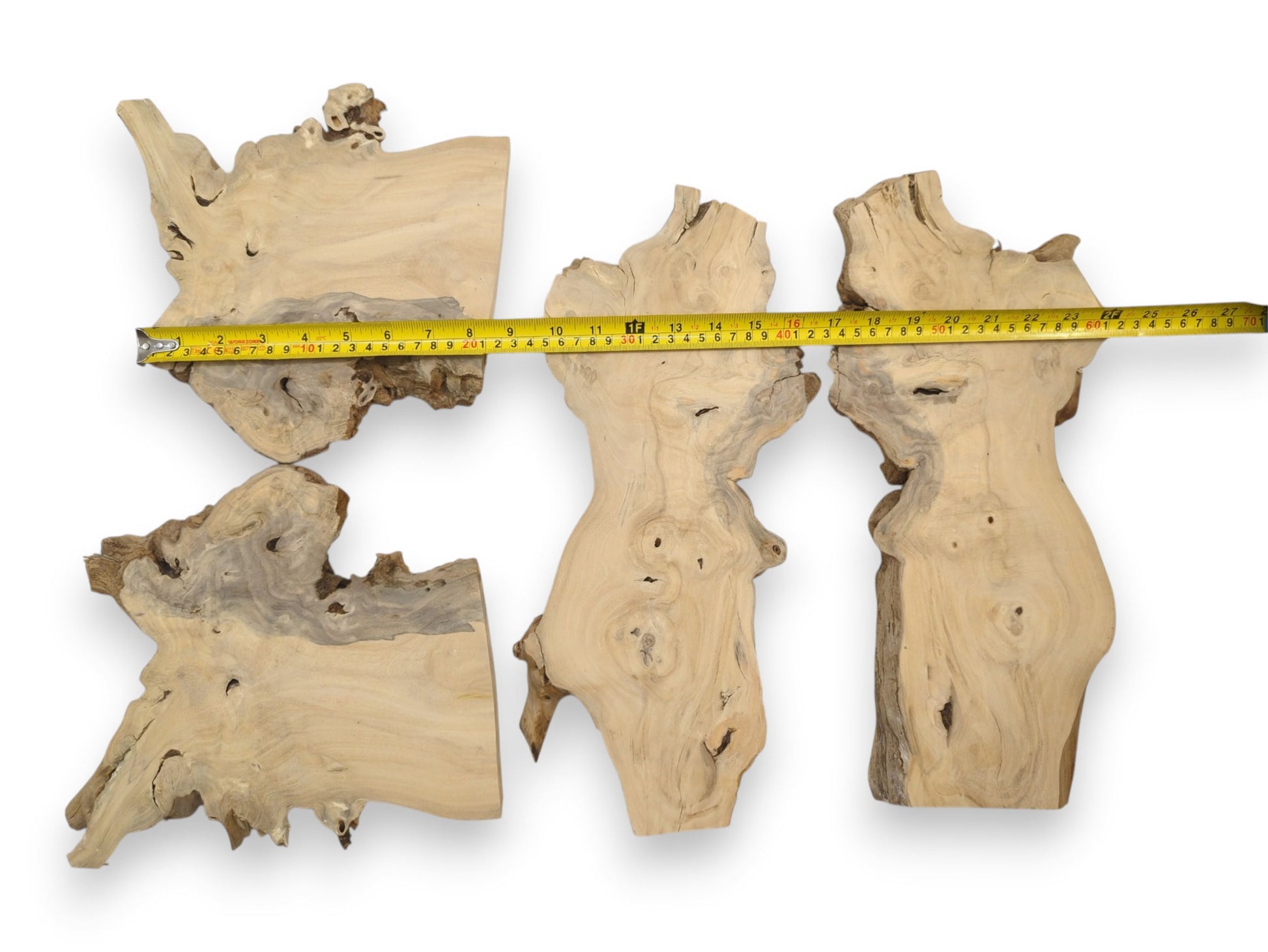 A yellow tape measure spans four pale, organic-shaped wood cuts with unfinished, bark-lined edges.