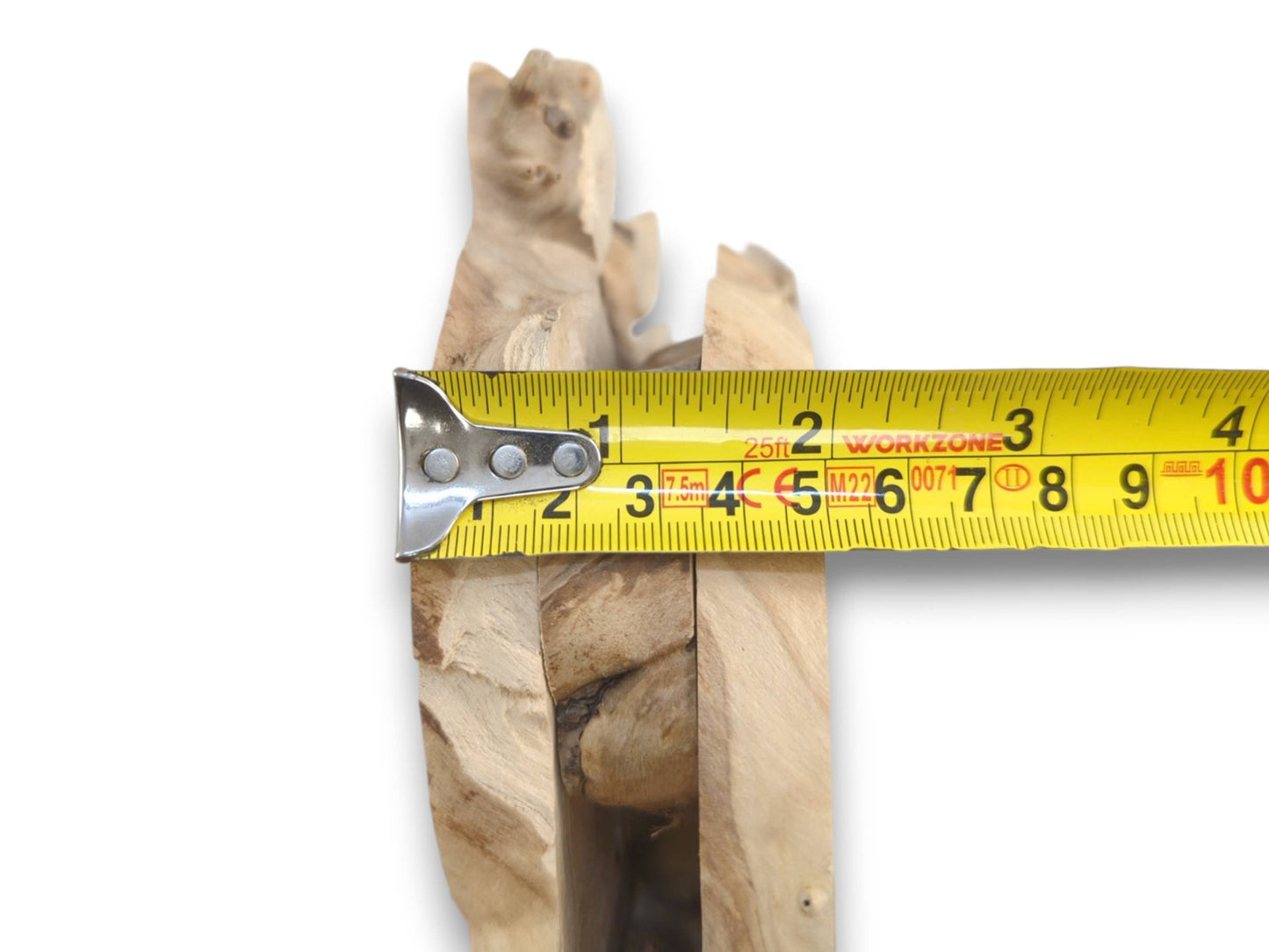 Three light-colored, irregularly shaped elderberry root wood pieces measured with a yellow tape.