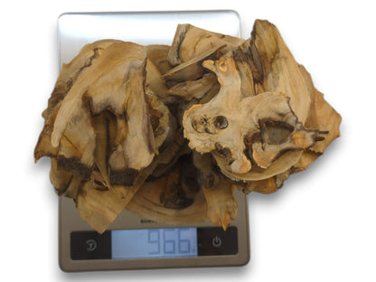 A pile of light-colored elderberry wood pieces with dark edges on a digital scale.