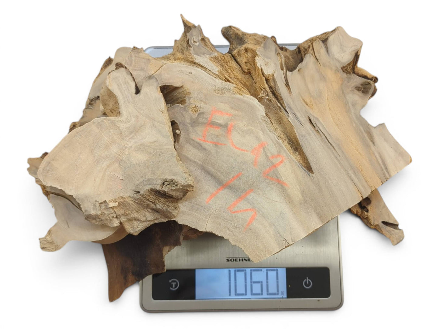 Several light-colored elderberry wood pieces with natural edges stacked on a digital scale.