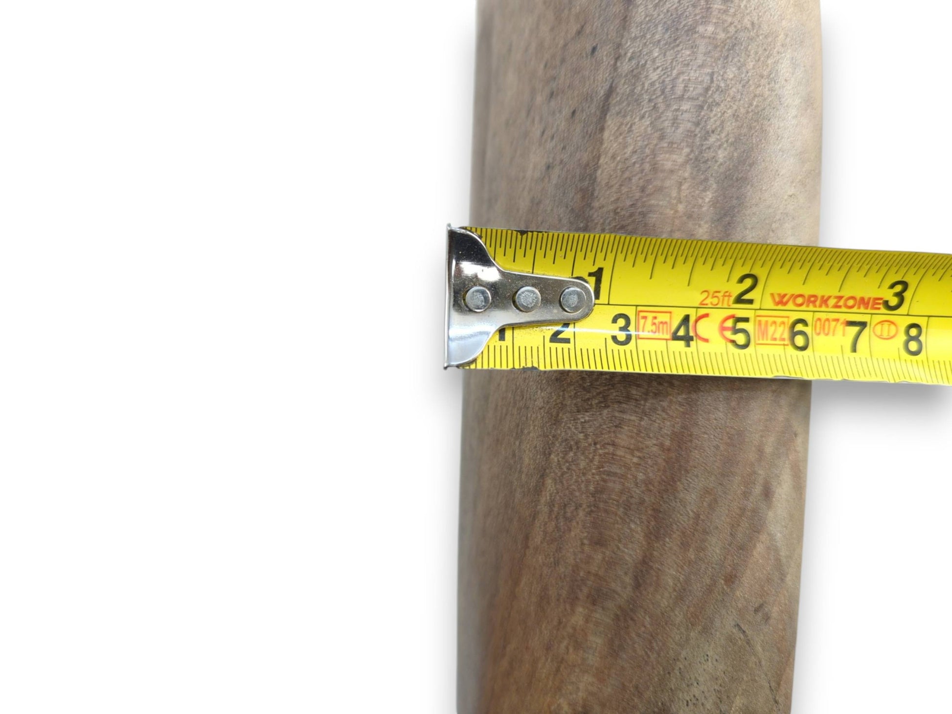 A tape measure's metal end hooks onto the thick, curved side of a walnut heart.