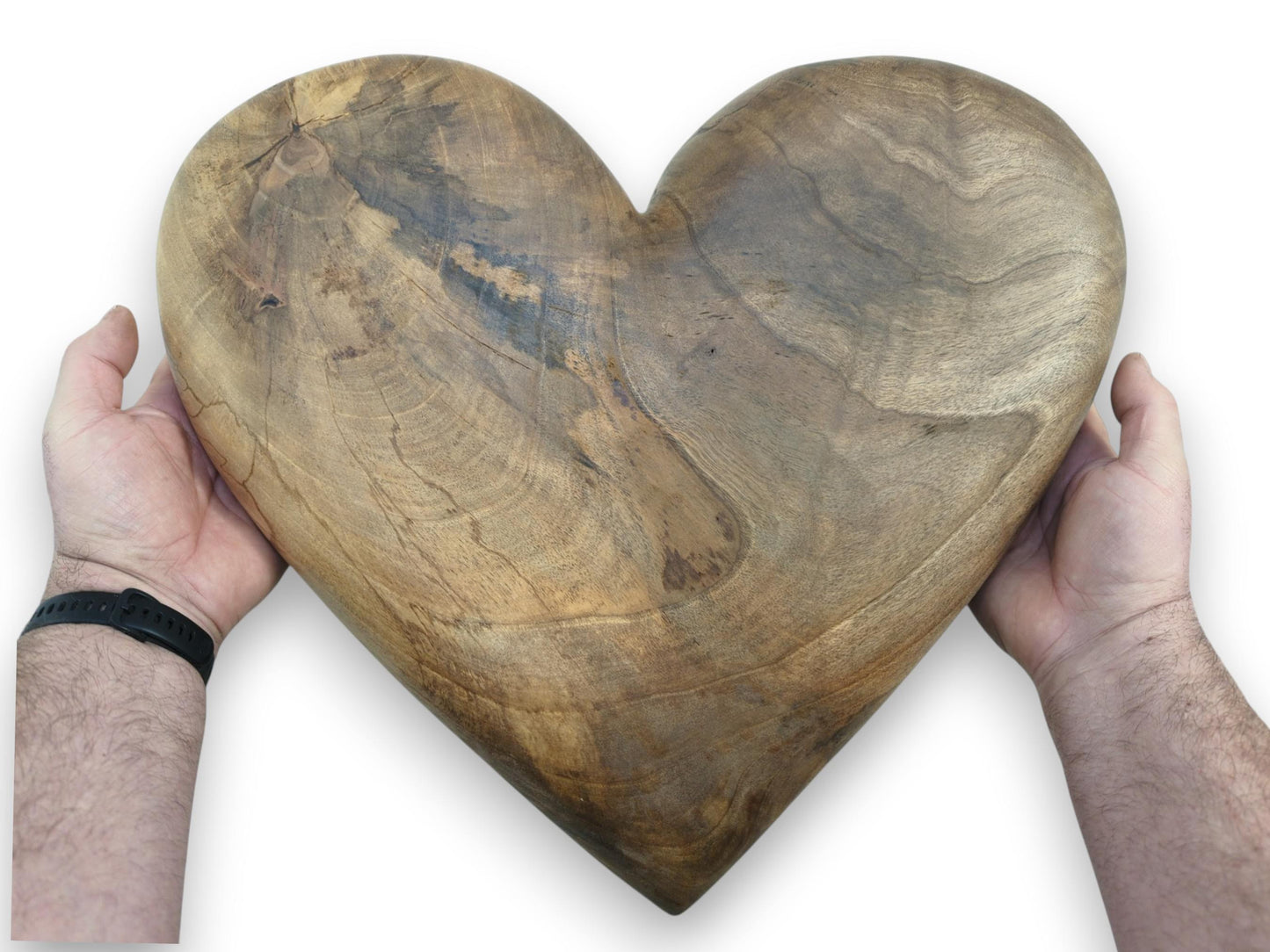 A person's hands cradle a large, carved walnut heart with prominent, smoky mineral streaks.