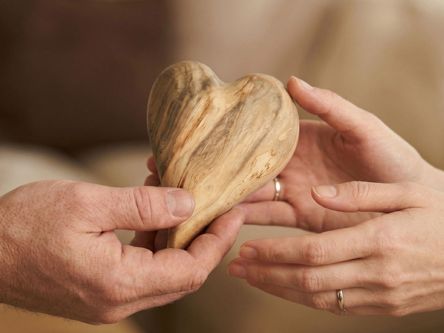 A close-up shows a heart-shaped timber with dramatic, wavy grain passed between two hands.