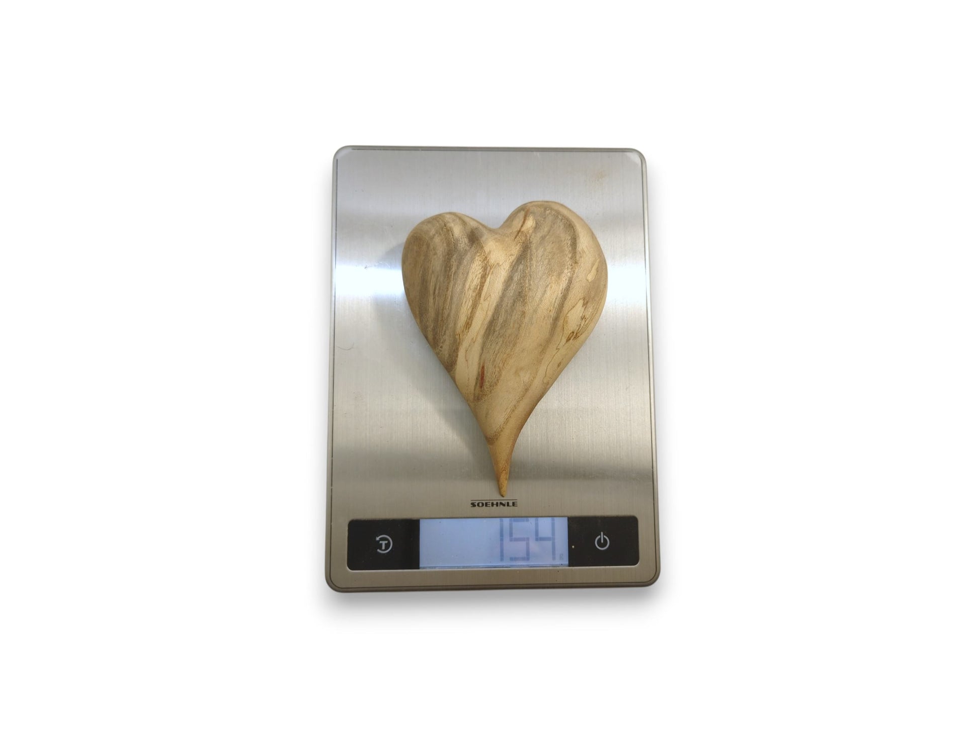 A heart-shaped wood carving with swirling grain sits on a digital scale reading 154.