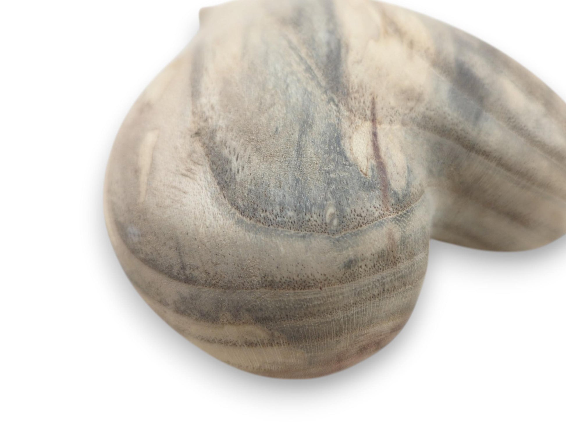 A close-up on a carved heart reveals porous end grain curving through marbled gray wood.
