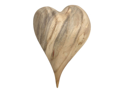 A pale wood heart carving features smoky grey figuring and an elongated pointed tip.