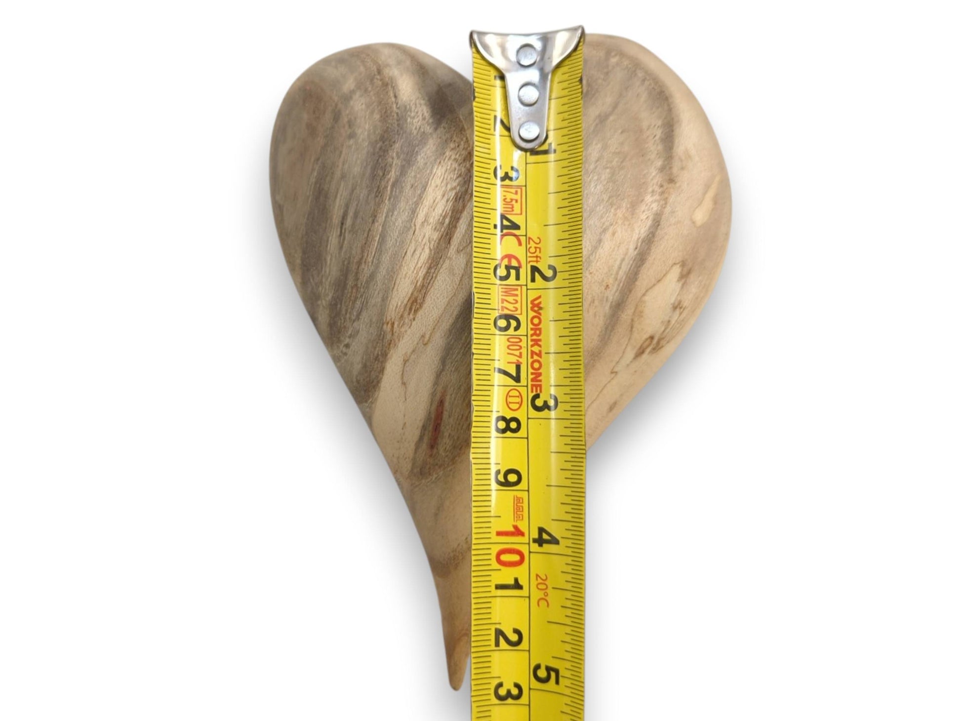 A yellow tape measure shows the height of a heart carving with dark, sweeping grain.