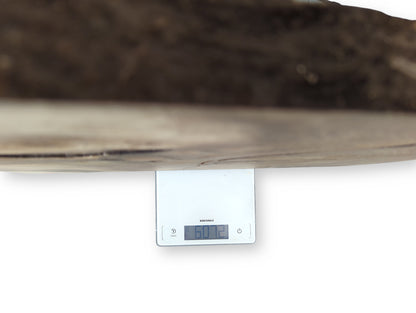 A thick wood slab, light brown, rests on a white digital scale displaying 60.72.