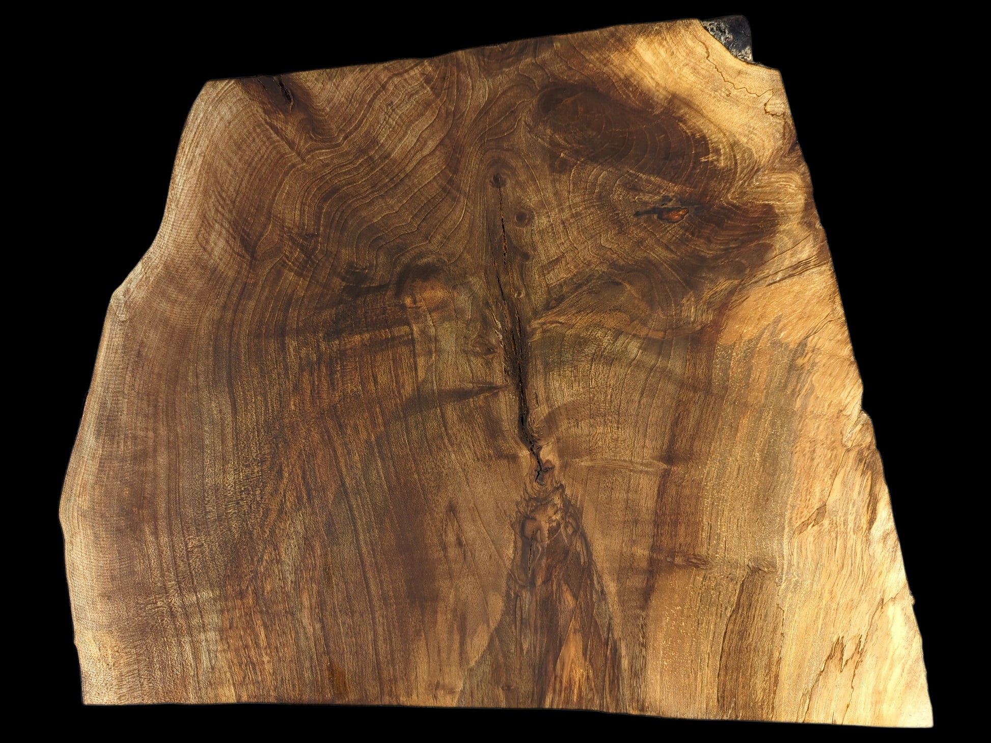 A live edge English Walnut wood slice, irregularly shaped, with rich brown-golden grain and a central crack.