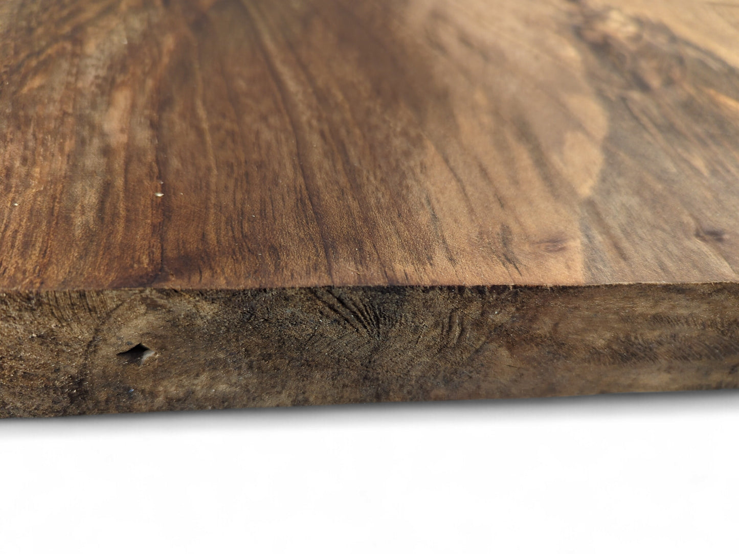 Close-up of a dark brown walnut wood slab, displaying its smooth top and textured edge with a small hole.