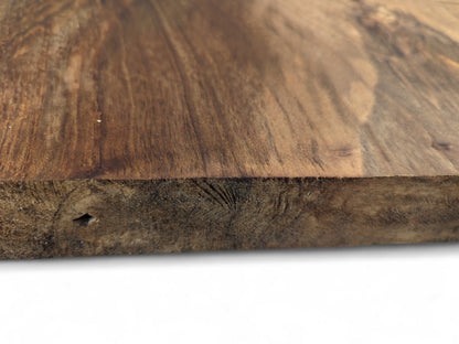 Close-up of a dark brown walnut wood slab, displaying its smooth top and textured edge with a small hole.