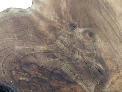 Walnut wood slice surface exhibits varied brown tones, prominent swirling grain patterns, and numerous natural fissures.