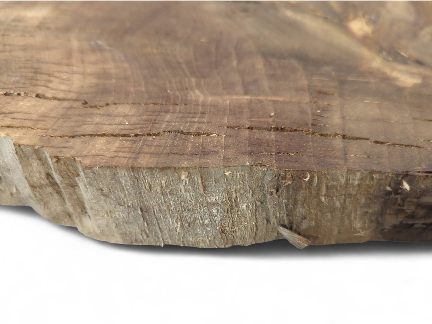 Brown irregular wood slice showing its grainy surface with horizontal cracks and a rough, textured natural edge.