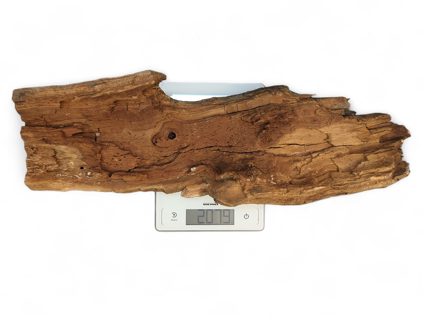 Nature-shaped, reddish-brown wood fragment with bark and cracks, resting on a digital scale displaying 207.9.