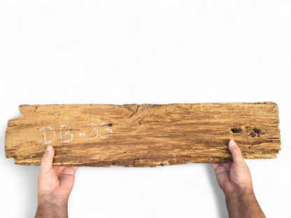 Hands holding a long, light brown wood slab with flaking, crumbly texture and "DB-33" in white.