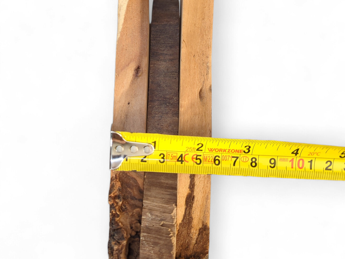 Assorted brown wood slices with rough live edges are measured by a yellow tape.