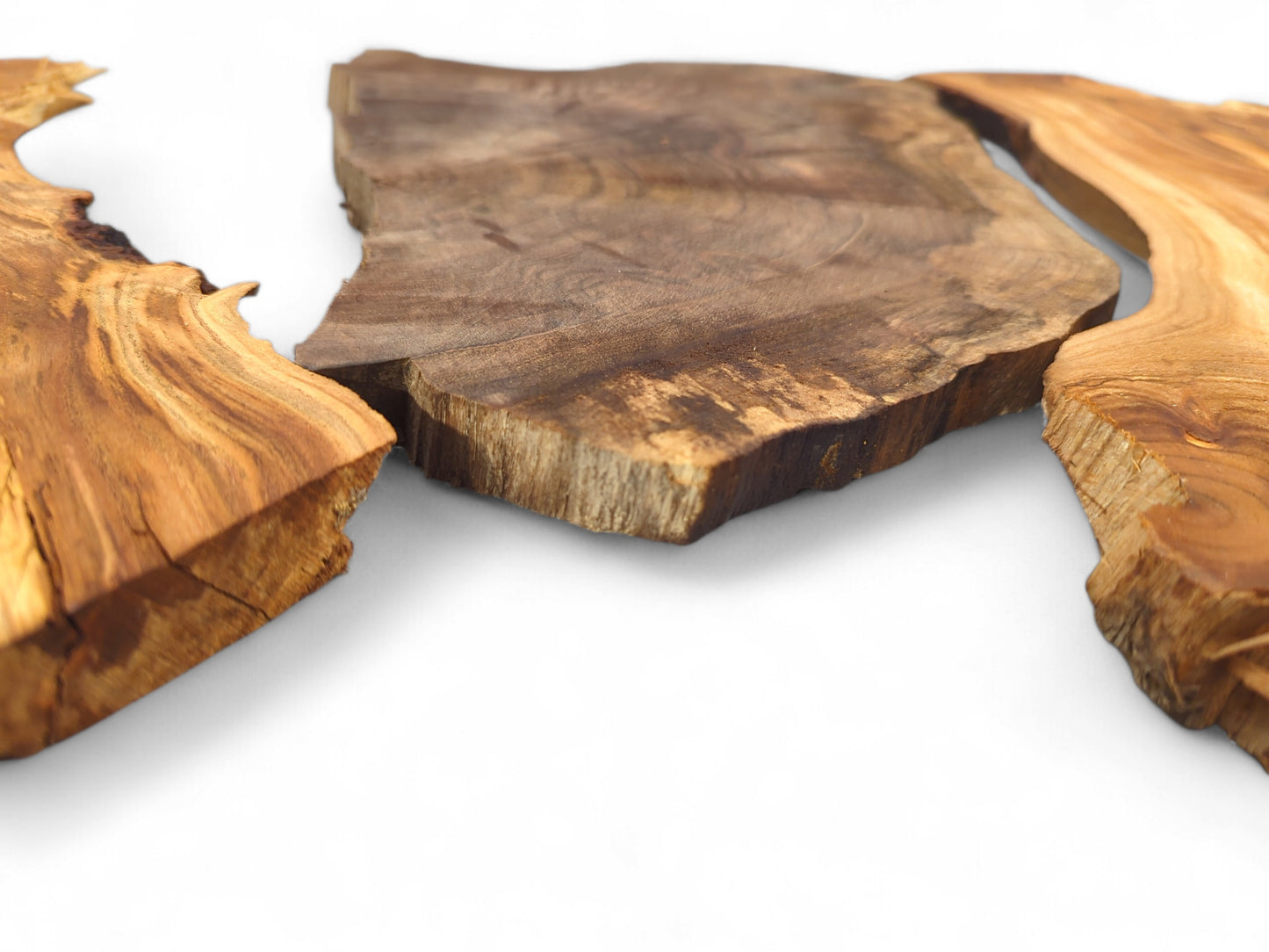 Three irregular, unfinished wood slices in varying brown tones, showing distinct natural grain and rough edges.