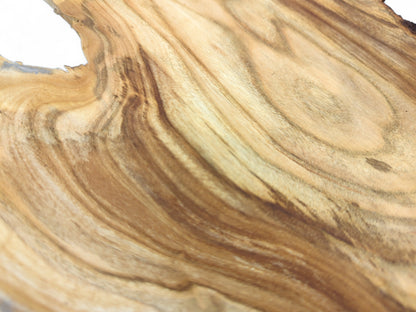 Close-up of an unfinished wood slice with smooth surface, featuring wavy brown grain and an irregular top edge.
