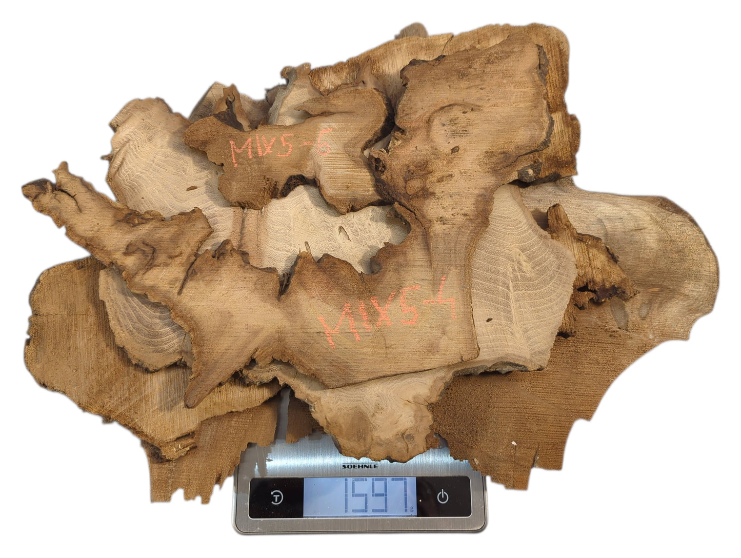 Irregular thin brown wood slices with red text markings are piled on a digital scale showing 1591g.