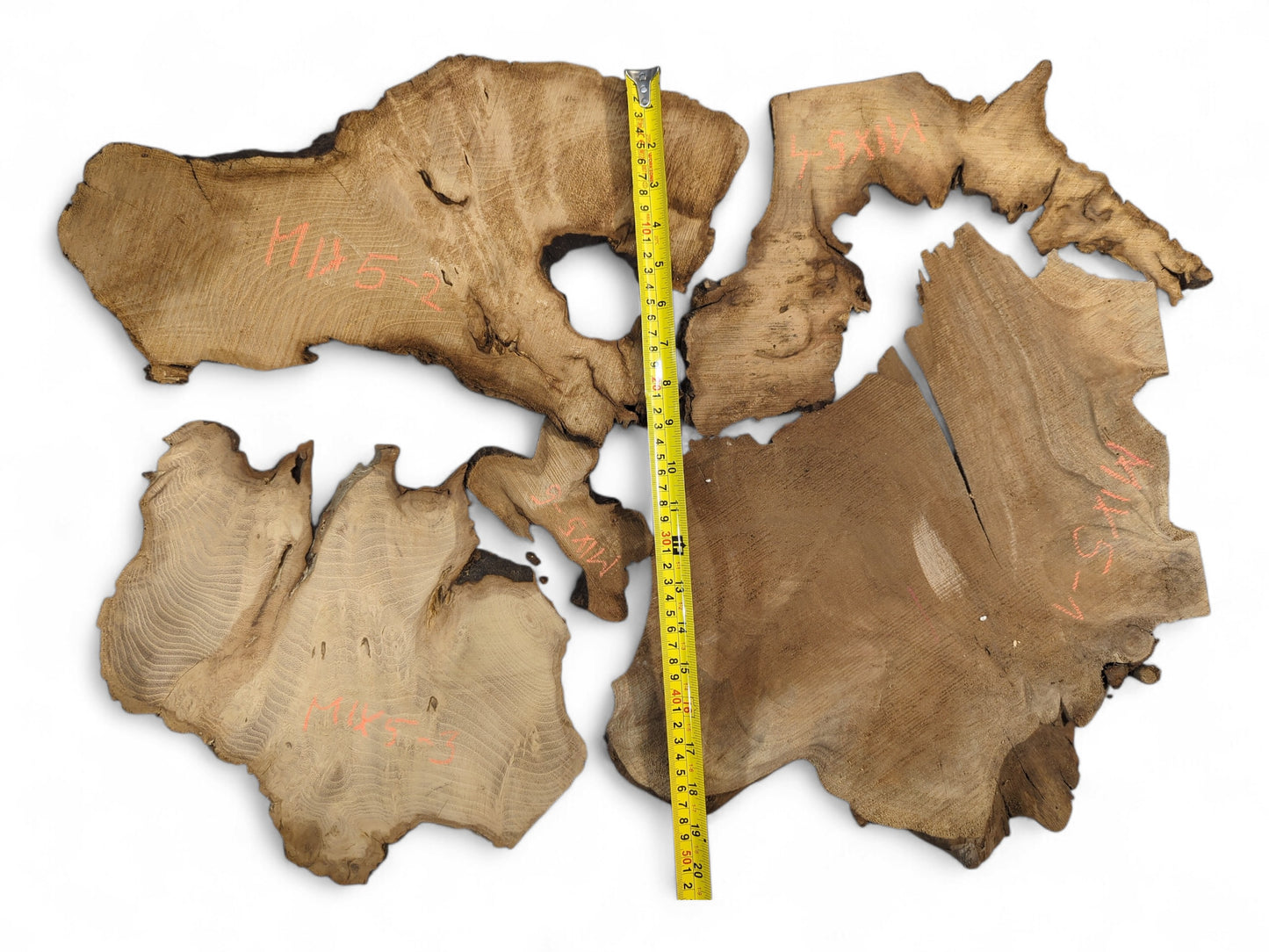 Multiple irregular brown wood slices with prominent grain, dark live edges, and a yellow tape measure.