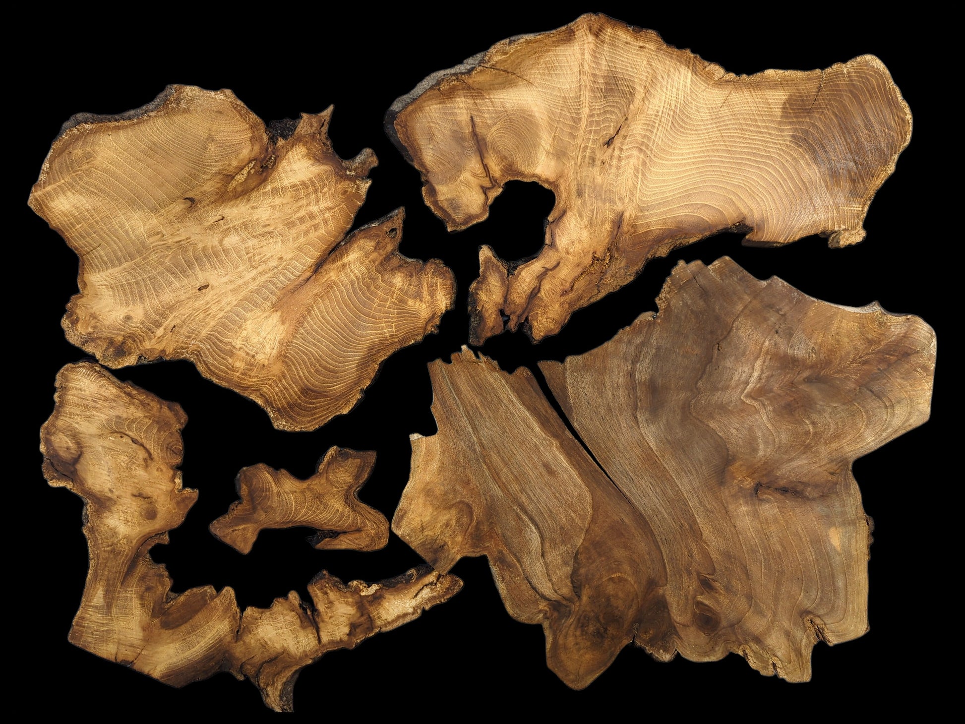 Several irregular, thin, brown wood slices with live edges and distinct grain patterns on a black background.