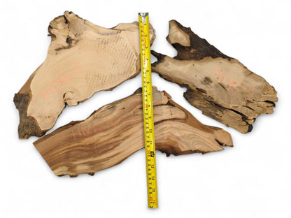 Three irregular live edge wood slices display varied brown tones, visible grain, red text, and a yellow measuring tape.