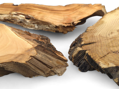 Three irregular, unfinished wood slices with light brown surfaces, prominent grain, and dark, rough live edges.
