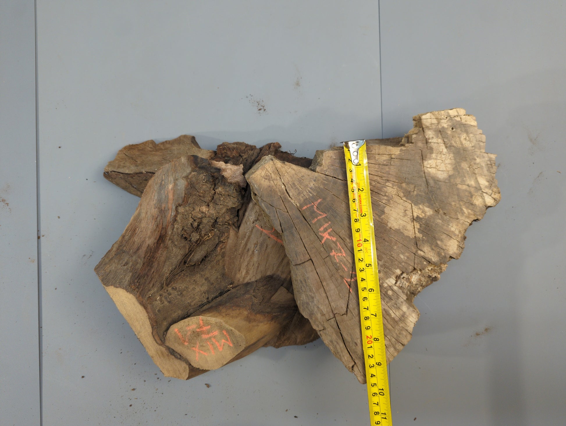Several irregular, live-edge wood slices, some wedge-shaped, with red markings and a yellow measuring tape.