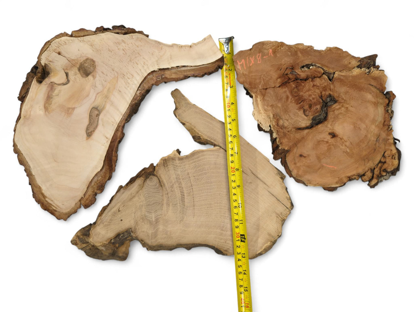 Three irregular wood slices, light to dark brown, with live edges and a yellow tape measure.