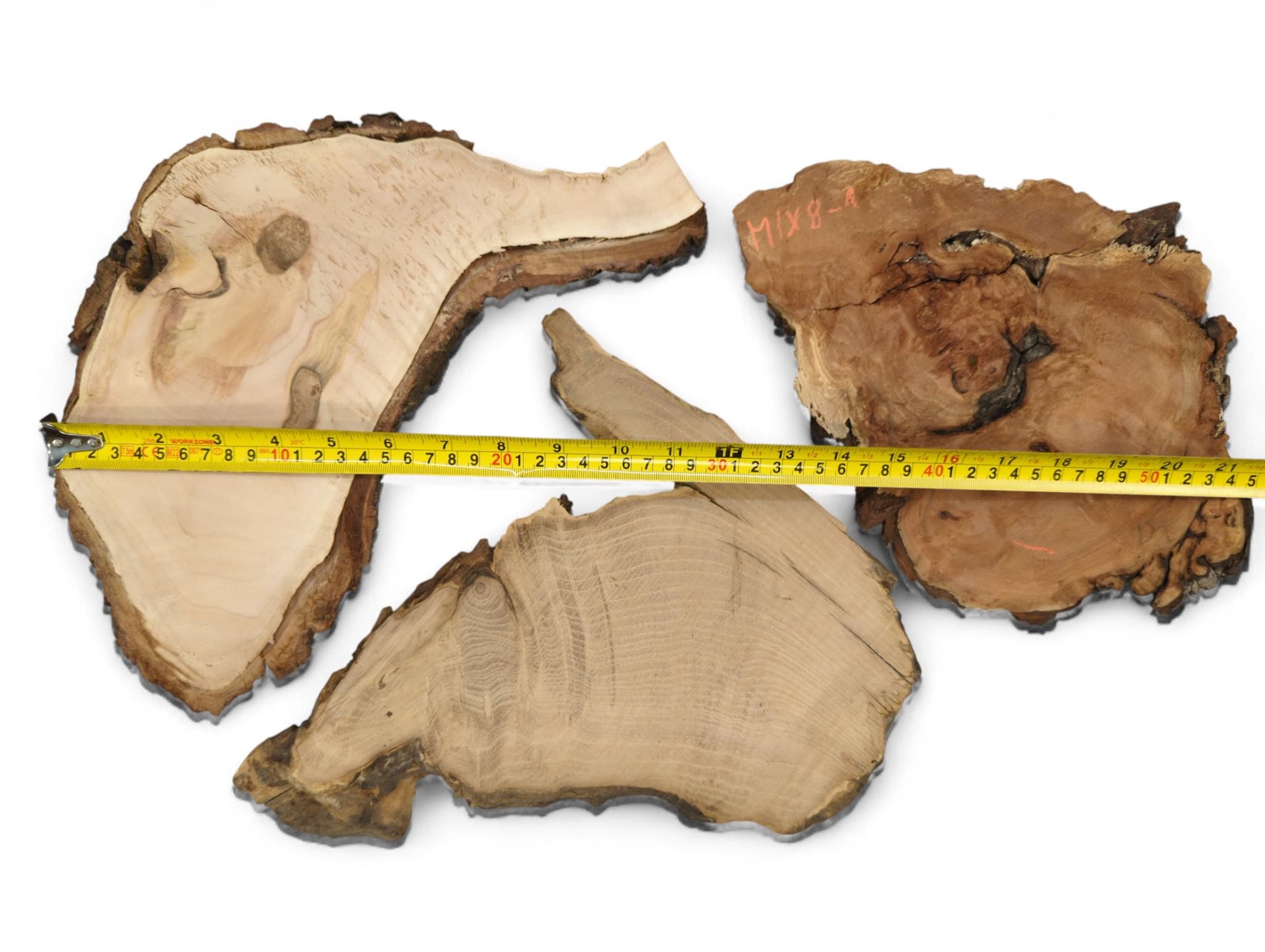 Several irregular, raw wood slices with light and dark live edges, measured by a yellow tape.