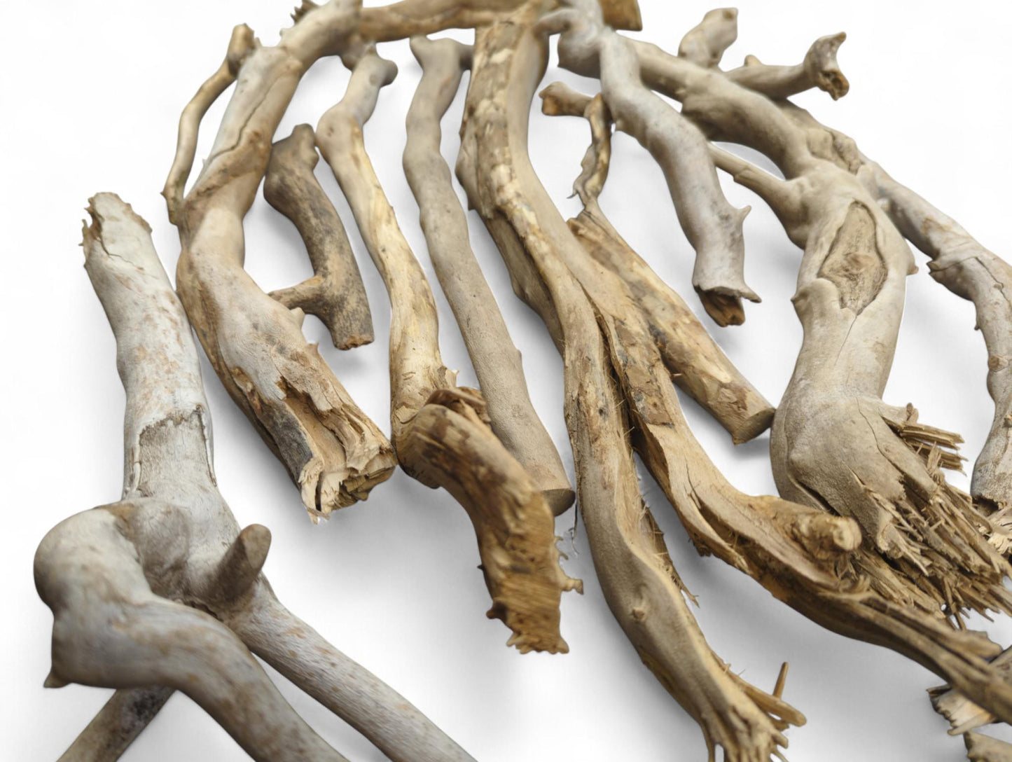 Scattered natural weathered driftwood branches, featuring varied irregular shapes and textures, in light brown, gray, and beige.