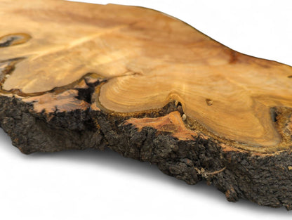 Close-up of an irregular light brown cherry wood slice, showing textured bark and unique grain patterns.