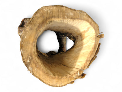Gnarled, hollowed natural wood log, showing rough, dark brown bark and a smooth, pale inner passage.