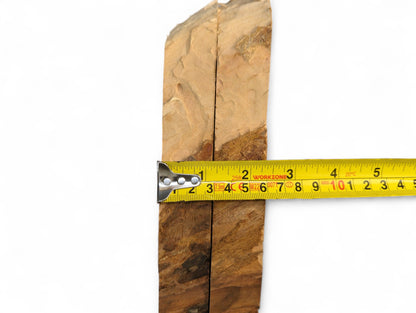 Two light brown bookmatched wood slices with natural edges and visible grain, measured by a yellow tape.