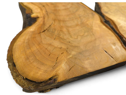 Golden-orange wild cherry wood slice, showing an irregular live edge, visible annual rings, and surface cracks.