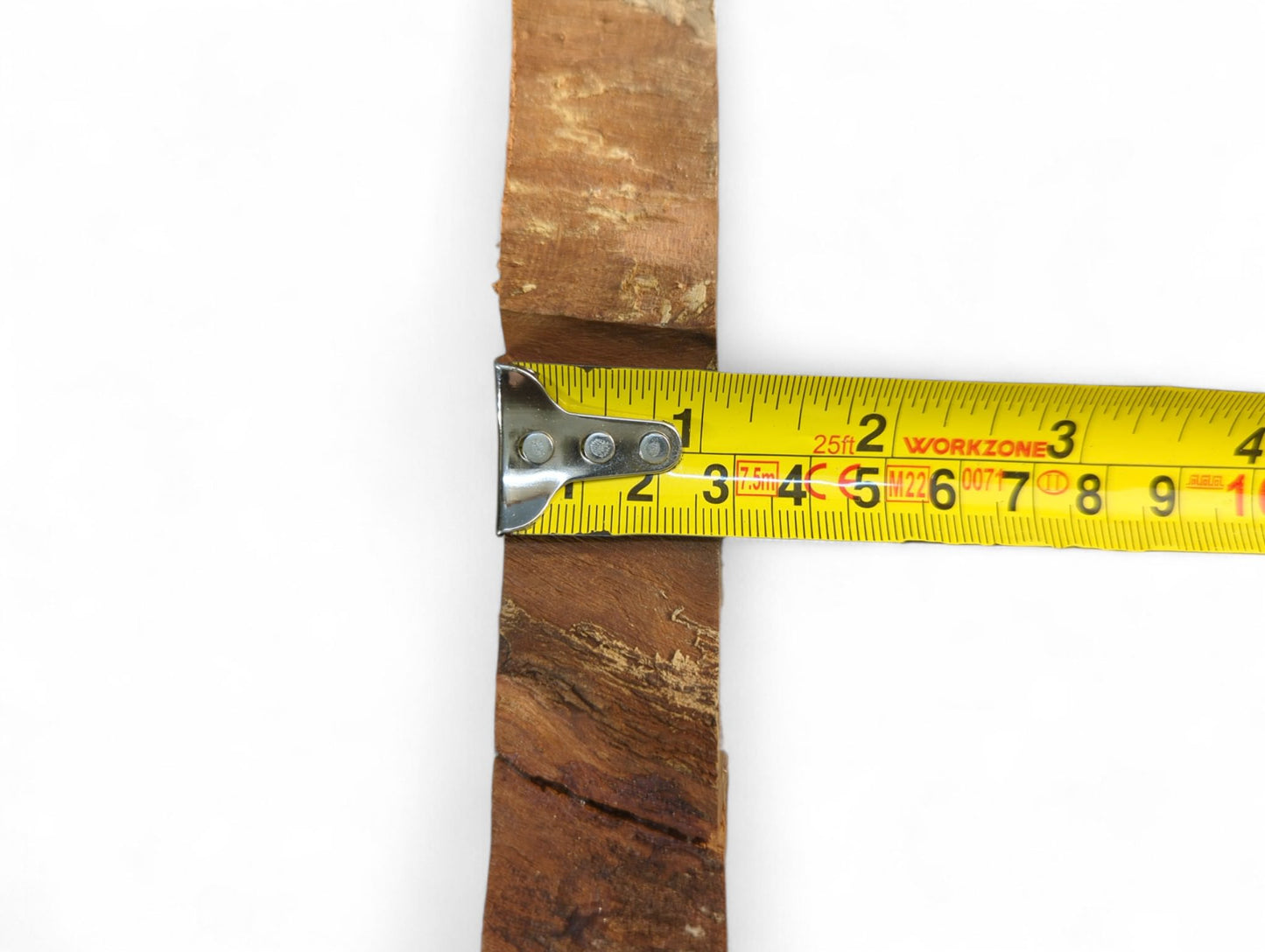 A reddish-brown cherry wood slice with natural live edges measured by a yellow tape measure.
