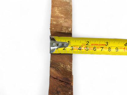 A reddish-brown cherry wood slice with natural live edges measured by a yellow tape measure.