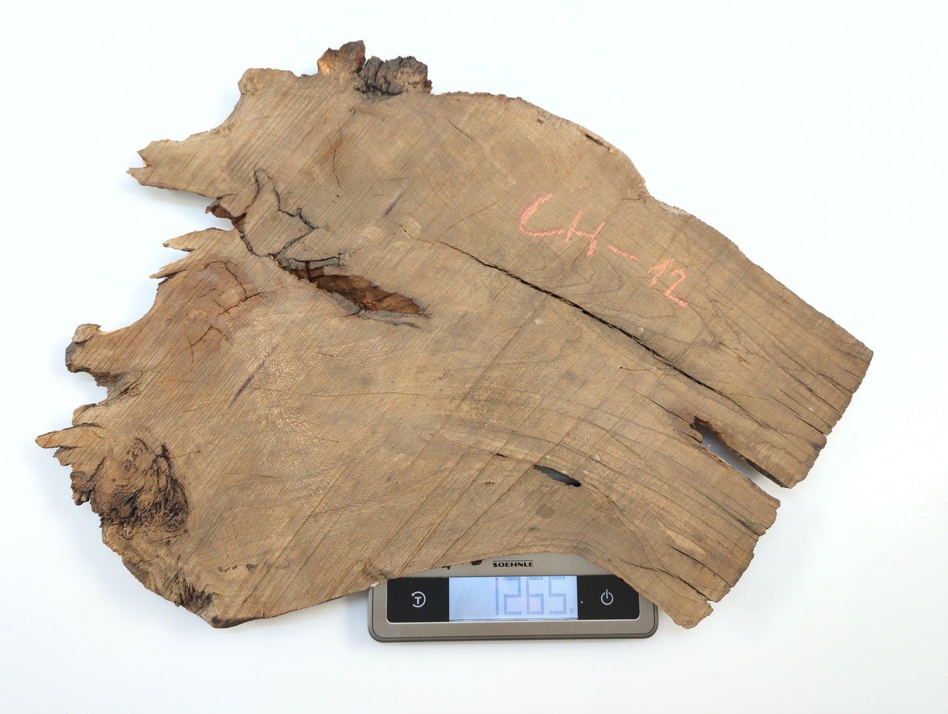 A raw, irregular wild cherry slab marked CH-12 is placed on a digital scale showing its weight.