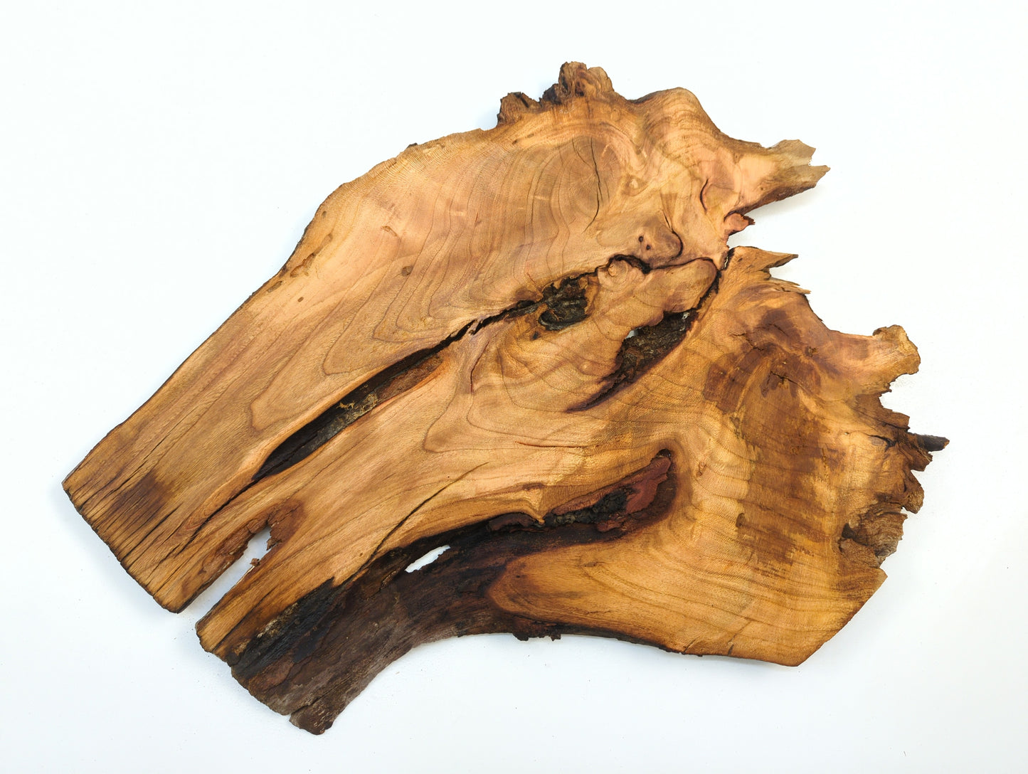 A single wild cherry wood slab with an irregular shape, showing its grain and natural fissures.