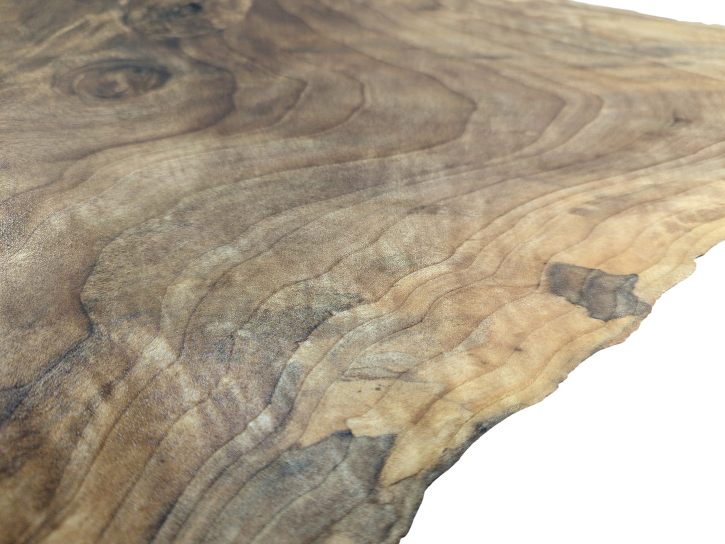 An angled, close-up photograph of a walnut slab highlighting its undulating wood grain and natural edge.
