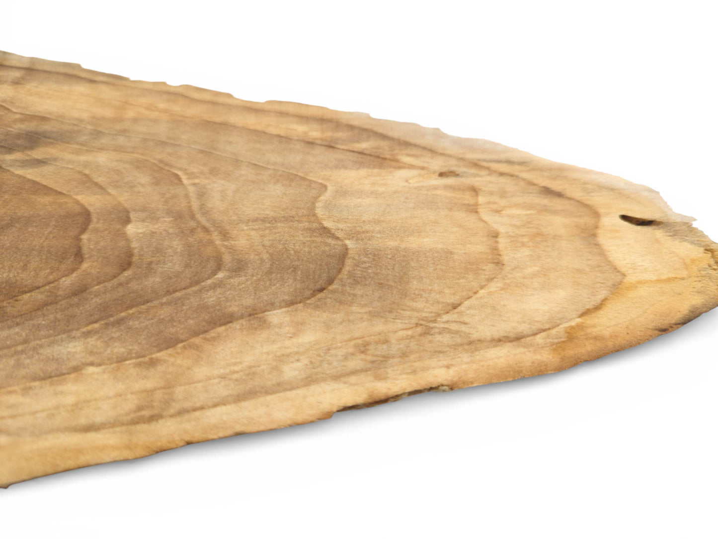 A diagonal perspective across a light brown wood slab, detailing its contoured grain and raw edge.