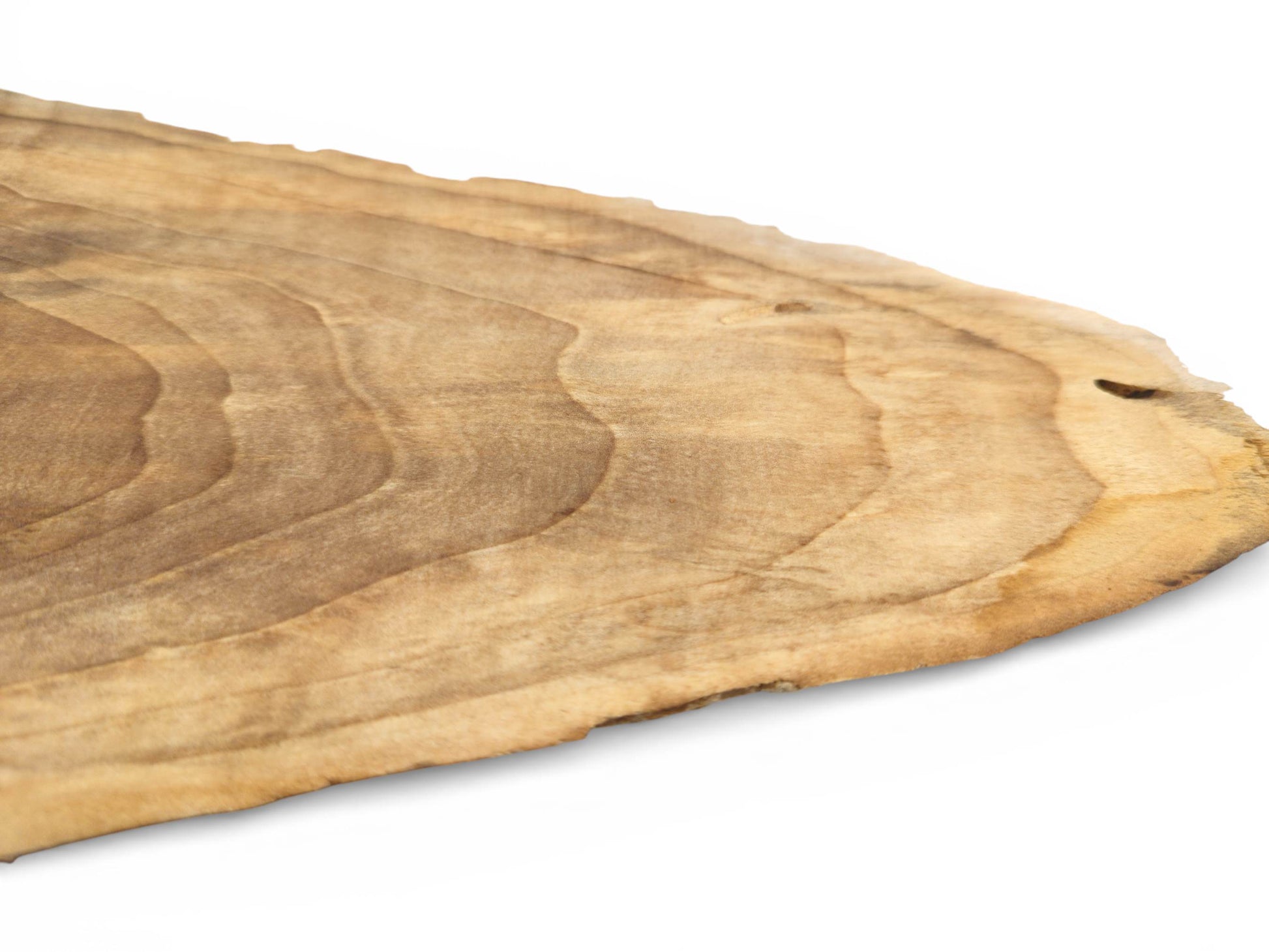 A diagonal perspective across a light brown wood slab, detailing its contoured grain and raw edge.
