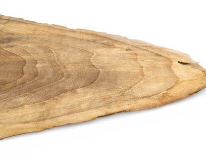 A diagonal perspective across a light brown wood slab, detailing its contoured grain and raw edge.