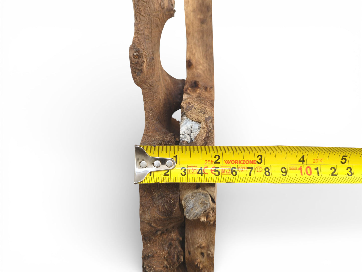 A vertically oriented piece of rustic wood with a yellow measuring tape showing its width.