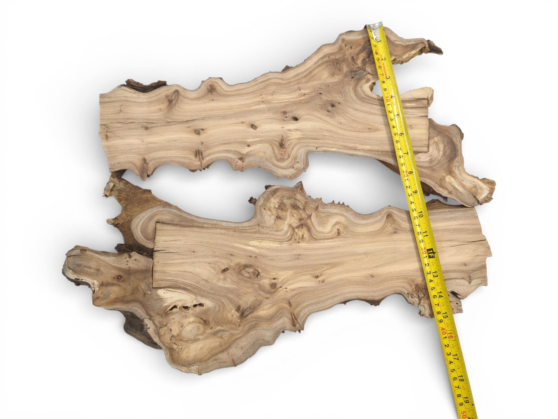 An overhead shot of two irregular wood pieces, their combined length indicated by a tape measure.